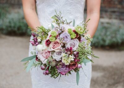 Fulham Palace Bride holding violet and pink rose bouquet